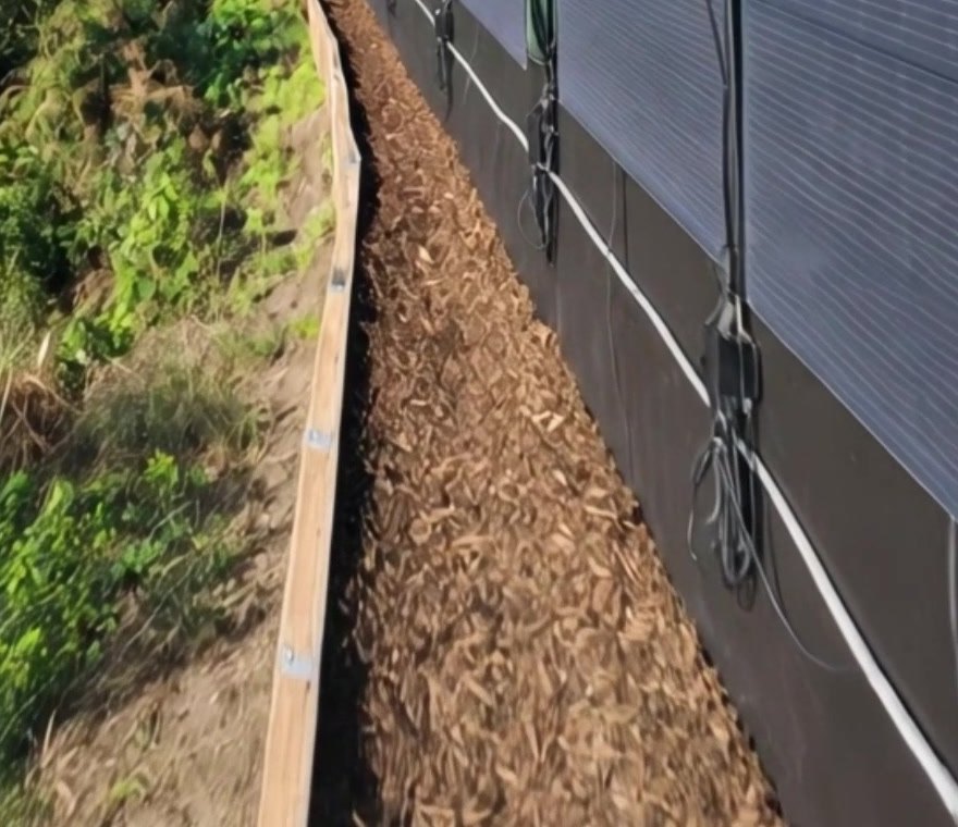 Cavi di uscita MC4 di moduli solari flessibili verticali lungo la parte bassa di una recinzione da giardino